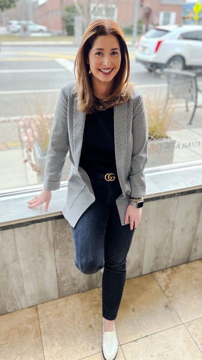 Image of Amanda posing while leaning on glass wall smiling
